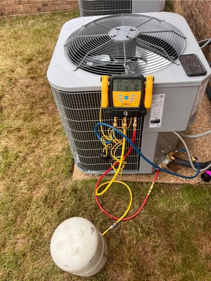 Outdoor condenser on a lawn with a digital manifold gauge set and hoses attached